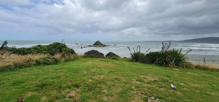 Monkey Island rising out of the surf, seen from the grassy bank above the beach